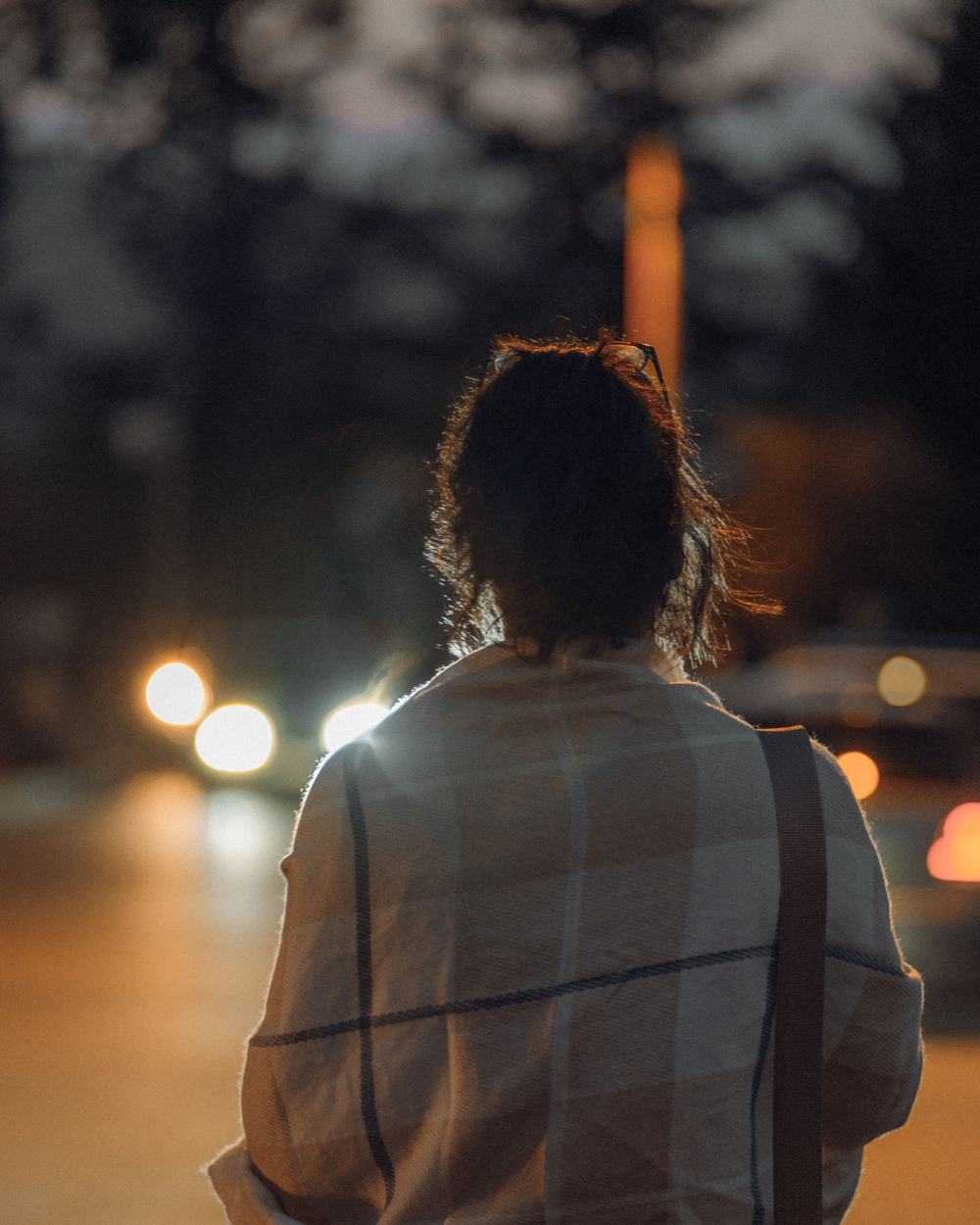 Camille Moreau, seen from behind in a checked shawl on a street at night.
